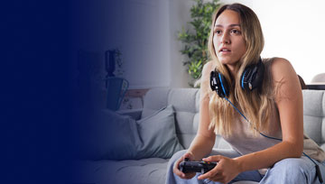 Woman gaming with headset, focused on screen at home.